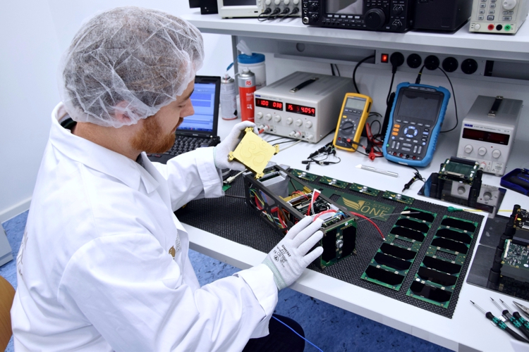 The D-Star One amateur radio satellite being assembled by a worker on a lab bench.